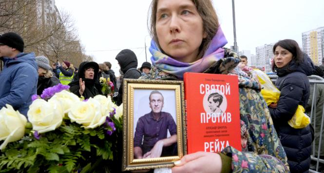 Pogrzeb Aleksieja Nawalnego w Moskwie, 1 marca 2024 r. Kobieta trzyma jego zdjęcie i książkę „Święty Przeciwko Rzeszy”, opowieść o Alexandrze Schmorellu, walczącym z nazizmem prawosławnym Niemcu o rosyjskich korzeniach.