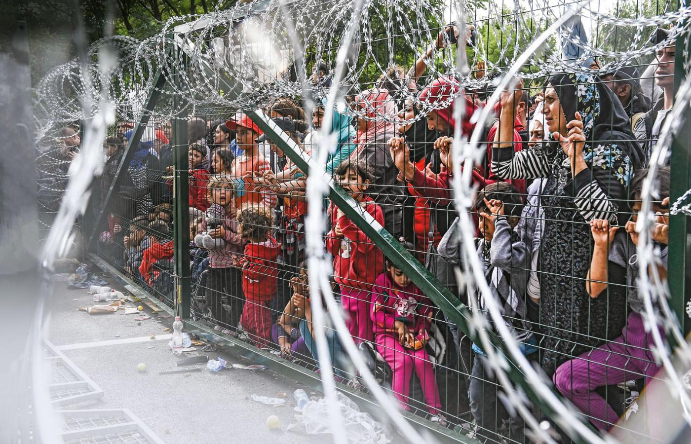 Uchodźcy na zadrutowanej granicy węgiersko-serbskiej w pobliżu miasta Horgos, 2015 r.