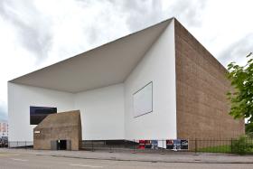 Muzeum Schaulager w Zurychu. Projekt zrodził się w pracowni duetu Herzog&de Meuron. W budynku mieści się kolekcja dzieł sztuki Fundacji Emanuel Hoffmann, a jej rolą jest nie tylko zachwycać, ale też edukować. To aż 650 prac najważniejszych twórców współczesnych (dość wymienić Salvadora Dalego i Paula Kleego). Duet architektoniczny miał więc za zadanie zapewnić tej sztuce właściwą oprawę. Obiekt ma 20 tys. m kw. powierzchni i kształt zgrabnego wielokąta. Jego wklęsła część – to tutaj do muzeum się wchodzi – wygląda jak osobliwy dziedziniec. Całość zaś przypomina magazyn sztuki – w chlubnym rozumieniu słowa „magazyn”, rzecz jasna. Muzeum, zbudowane w 2003 r., dziesięć lat później zostało jeszcze rozbudowane. Prócz sal wystawowych mieszczą się więc tutaj także sale seminaryjne, audytorium, biblioteka i pokoje administracyjne. Dodajmy, że do budowy wykorzystano żwir, glinę i kamienie, które pozyskano, przekopując się przez fundamenty tego obiektu. Wyszło więc i efektownie, i ekonomicznie.
