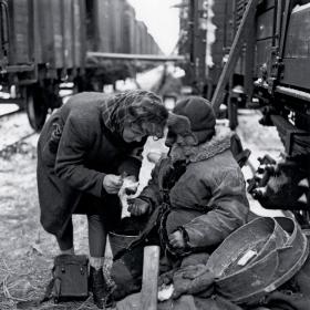 Pracownica Czerwonego Krzyża udziela pomocy przesiedleńcowi w punkcie etapowym, luty 1946 r.