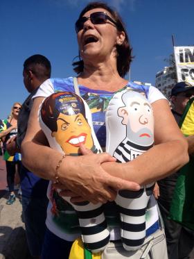 Demonstrantka trzyma figurki-baloniki Dilmy i Luli w pasiakach więziennych