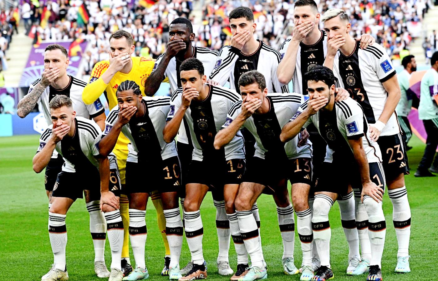 Niemieccy piłkarze zakrywają usta przed meczem z Japonią.