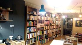 Czerwony Atrament, Płock, ul. Kolegialna 4/51. Dlaczego warto prowadzić księgarnię kameralną?Czerwony Atrament to księgarnia i kawiarnia, ale także przedsiębiorstwo działające na rynku kulturalnym, marketingowym oraz dystrybucji kawy speciality (chcemy rozkochać w niej płocczan i w szerszych planach – cały kraj ;)). Istnieje od niedawna, firmę założyłem we wrześniu po odejściu z lokalnego oddziału „Gazety Wyborczej”. Po remoncie de facto pustostanu w samym sercu – bądź co bądź – opustoszałej starówki pięknego Płocka w styczniu księgarnia i kawiarnia rozpoczęła działalność, którą wprost można nazwać minirewolucją w mieście.Tworzyć kameralnie warto dla siebie i dla innych ludzi, którzy wciąż rozumieją wartość książki. Prowadzenie księgarni niezależnej w obecnej sytuacji kulturalnej, społecznej i rynkowej naszego kraju to nie tylko sposób na biznes – to możliwość realizowania misji. Zależy mi na Płocku, tym niemałym, ale też niedużym mieście. Chcę, aby jego mieszkańcy mogli znaleźć w takim miejscu jak Czerwony Atrament przystań do obcowania z drugim człowiekiem, do intelektualnego rozwoju, do kulturalnych uniesień. Miejsce, w którym bez konieczności wyjazdu do pobliskich Warszawy czy Łodzi mogą zakupić albo chociaż przejrzeć świetną literaturę, której sporo jest wydawanej w Polsce. A także, wypić świetną kawę, której tutaj bardzo brakowało – robimy ją ręcznie, tworząc póki co mały, ale dobrze zorganizowany zespół ludzi od kawy i książki. Dla mnie, jako twórcy księgarni, to też świetna przygoda, która trwa wraz z kolejnymi książkami wypływającymi z Czerwonego Atramentu do domów kolejnych klientów. I oddaje swój sens wraz z kolejnymi osobami, które ucieszone z zakupionej lektury, sięgają tutaj po następne tytuły, rozwijając siebie.2. Skąd pomysł na taką, a nie inną nazwę księgarni?Przetoczę fragment przemówienia wygłoszonego na wiecu protestacyjnym Occupy Wall Street (Liberty Plaza, Nowy Jork, październik 2011) przez Slavoja Žižka: „Opowiem wam wspaniały dowcip z czasów komunistycznych. Gościa z NRD wysłano do pracy na Syberii. Wiedział, że jego listy będą czytane przez cenzurę. Powiedział więc swoim przyjaciołom: »Ustalmy kod. Jeśli dostaniecie ode mnie list napisany niebieskim atramentem, to, co napisałem, jest prawdą. Jeśli list będzie napisany czerwonym atramentem, to nieprawda«. Po miesiącu przyjaciele otrzymują pierwszy list. Cały na niebiesko. Czytają w nim, że wszystko jest tam wspaniałe. Sklepy są pełne dobrego jedzenia. W kinach wyświetlane są filmy z Zachodu. Mieszkania są duże i luksusowe. Jedyna rzecz, której nie da się kupić, to czerwony atrament.Tak właśnie wygląda nasze życie. Mamy całą wolność, jakiej można pragnąć. Brakuje nam jednak czerwonego atramentu – języka, w którym moglibyśmy wyrazić brak wolności. Sposób, w jaki jesteśmy uczeni mówienia o wolności, wojnie, strachu i tak dalej, zafałszowuje wolność. I właśnie to robicie tutaj – dajecie nam wszystkim czerwony atrament”. W Płocku mamy już Czerwony Atrament. — Krzysztof Blinkiewicz.