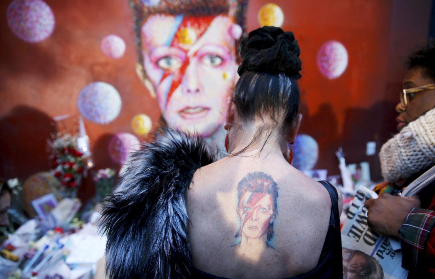 Kobieta z tatuażem Ziggy'ego Stardusta przy muralu Dawida Bowiego w Brixton w południowym Londynie, 11 stycznia 2016 r.