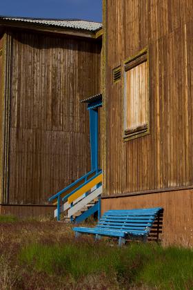 Świeżo odmalowana ławka pod jednym z zabitych deskami domów.