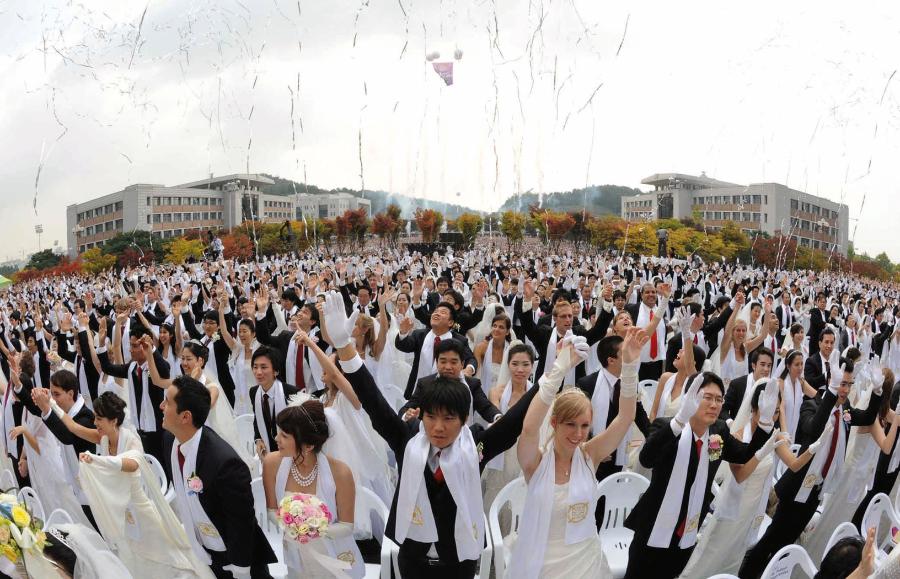 Nowożeńcy wznoszą okrzyki podczas masowej ceremonii ślubnej na Sun Moon University w Asan, na południe od Seulu. Masowe śluby stanowiły źródło dochodu Kościoła Zjednoczeniowego, znanego jako sekta Moona.