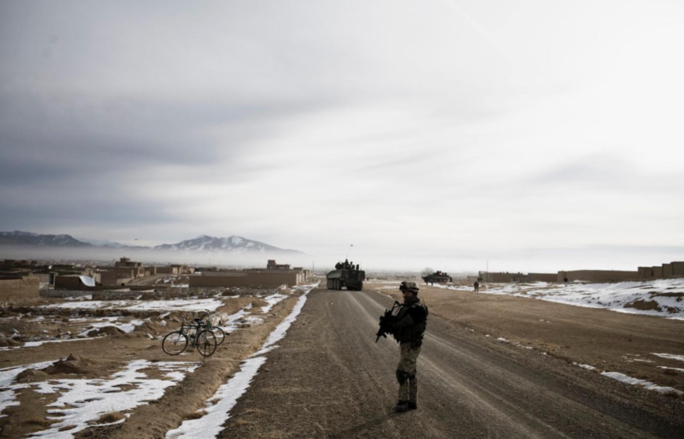 Patrol żołnierzy przed afgańską wioską (po lewej w głębi)