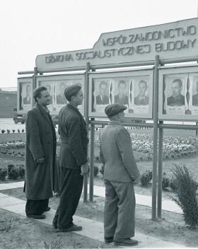 Przodownicy pracy Miszta, Miedlicki i Zawada przed tablicami współzawodnictwa w Nowej Hucie, 1953 r.