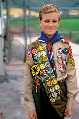 Skaut w mundurku i szarfie z odznakami sprawnościowymi.