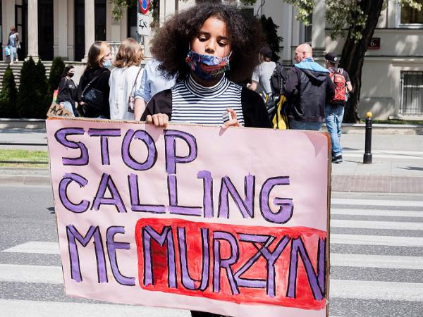 Protestująca pod ambasadą USA w Warszawie z plakatem „Stop calling me Murzyn”.