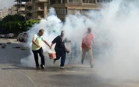 Demonstranci próbują jak najdalej uciec z wiadrami z gazem łzawiącym wyrzuconym przez policję w okolice meczetu Rabaa al-Adawija.