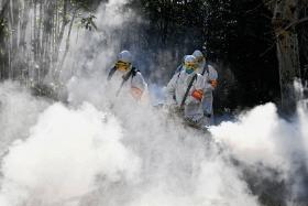 Pracownicy sanitarni dezynfekują tereny wokół osiedla mieszkaniowego w chińskim mieście Bozhou.