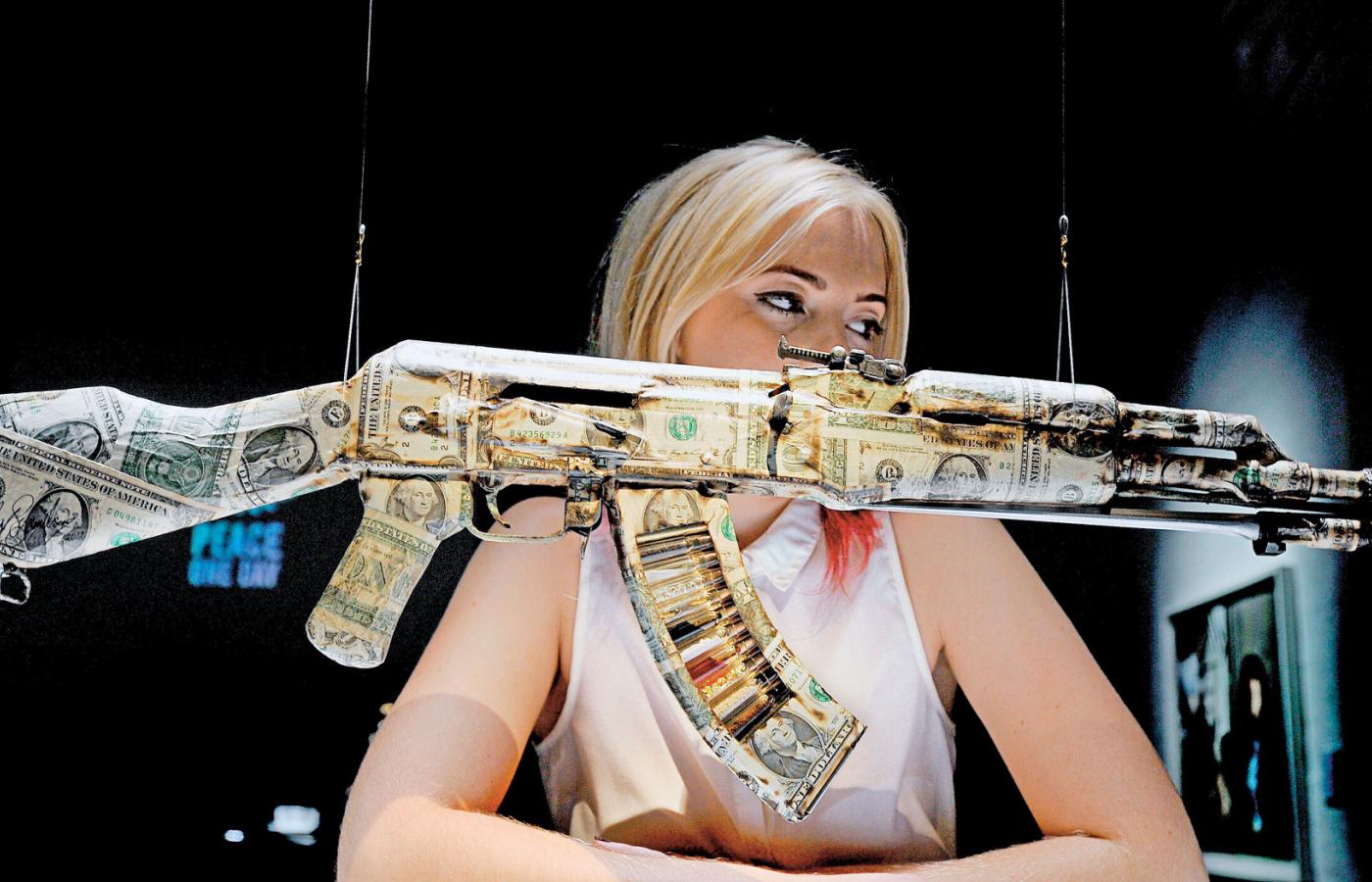 Emma Gilhooly z bronią oklejoną dolarami projektu Brana Symondsona w Institute of Contemporary Arts w Londynie.