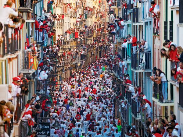 Ubrani w charakterystyczne białe i czerwone stroje mieszkańcy Pampeluny w północnej Hiszpanii przyglądają się corocznej gonitwie byków, która odbywa się na ulicach miasta z okazji święta ku czci św. Firmina.