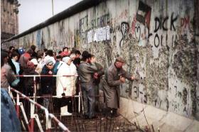 Mieszkańcy Berlina Zachodniego przy mocno zniszczonym murze w pobliżu Reichstagu w końcu 1989 r.