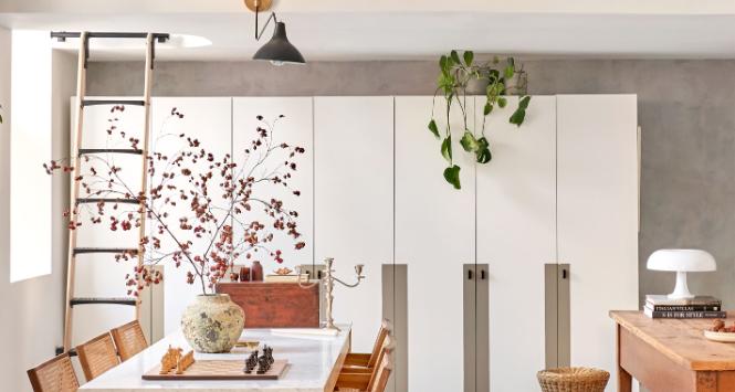 Widok z salonu na jadalnię i bibliotekę na antresoli. Zaraz po prawej jest otwarta kuchnia. Przestrzenie są tak zaprojektowane, że przenikają się płynnie, bez zgrzytów. Drewno swoją barwą rozgrzewa chłodne podłogi, ściany, fronty szaf i blat stołu.