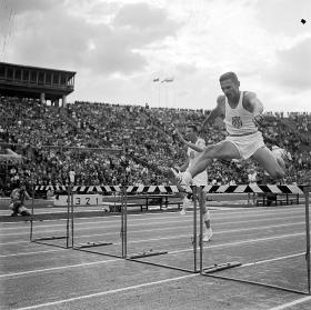 Mecz lekkoatletyczny Polska – USA w lipcu 1958 r. Goście lekko pokonują płotki przed lożą komentatorów i pełnymi trybunami.