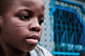 Młody wyznawca voodoo z ceremonialnymi bliznami na twarzy.