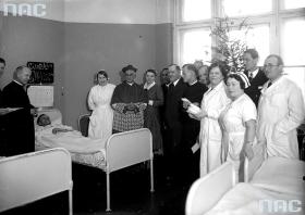 Arcybiskup metropolita krakowski Adam Sapieha dzieli się opłatkiem z chorymi spędzającymi święta Bożego Narodzenia w szpitalu przy ulicy Prądnickiej w Krakowie. Koniec lat 30. XX wieku.