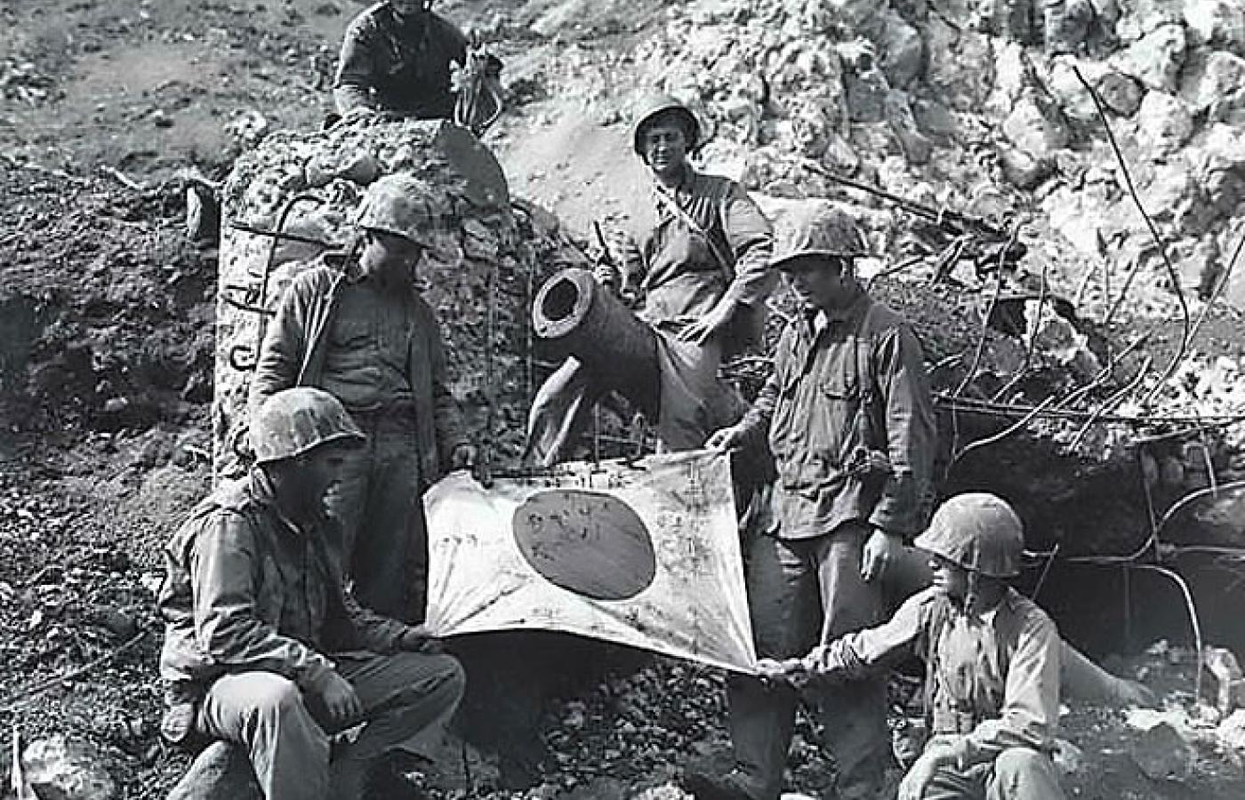 Amerykańscy żołnierze ze zdobyczną flagą na gruzach japońskiego bunkra