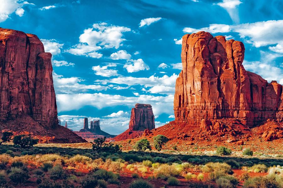 Malownicza Monument Valley na wyżynie Kolorado zbudowanej z płasko ułożonych warstw z ery paleozoicznej. Wiatr wyrzeźbił tu niezwykłe formy skalne.