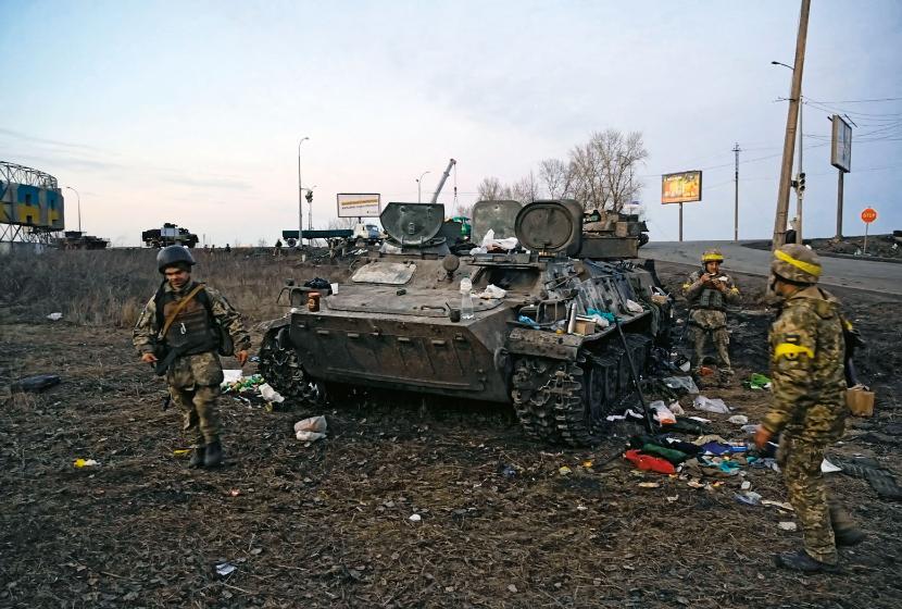 Ukraińscy żołnierze obok rosyjskiego transportera uszkodzonego pod Charkowem.