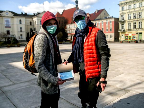 Mężczyźni rozdający maseczki na opustoszałym Starym Rynku w Bydgoszczy