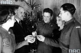 II wojna światowa. Rodacy starają się dochować tradycji mimo trudności i grozy dwu okupacji. Uchodźcy w Wielkiej Brytanii łamią sie opłatkiem podczas Wigilii. Lata 40. XX wieku.