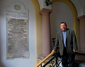 Dyrektor Jacek Hudziak w wejściu do administracji z niemiecką tablicą ku czci pracowników szpitala poległych w I wojnie światowej