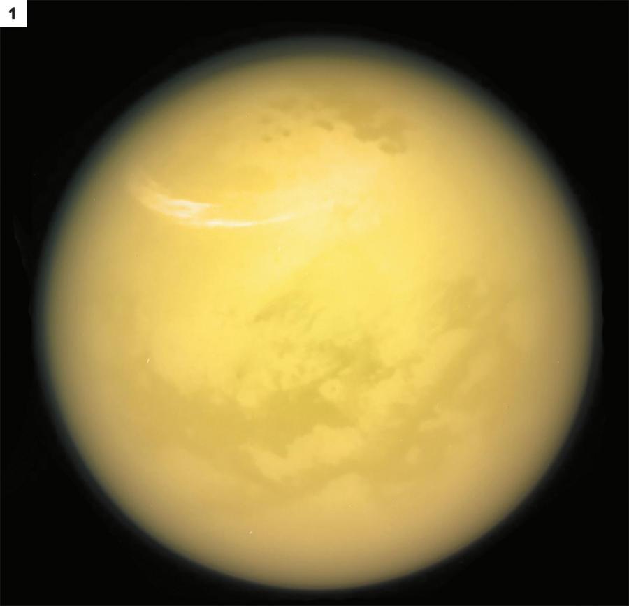 Tytan, największy księżyc Saturna, lśni blaskiem (kolory nieprawdziwe) (1) i majaczy w oddali (2) za mniejszym księżycem Enceladusem i pierścieniami planety.