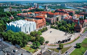 <b>„Przełomy”</b> to zaprzeczenie sąsiedniej filharmonii. Zamiast strzelistości Centrum cechuje horyzontalna rozłożystość. Zamiast ekstrawertyzmu i obnoszenia się z pięknem - skromność i introwertyzm. A zamiast zamknięcia się w bryle - otwarcie się na otoczenie.